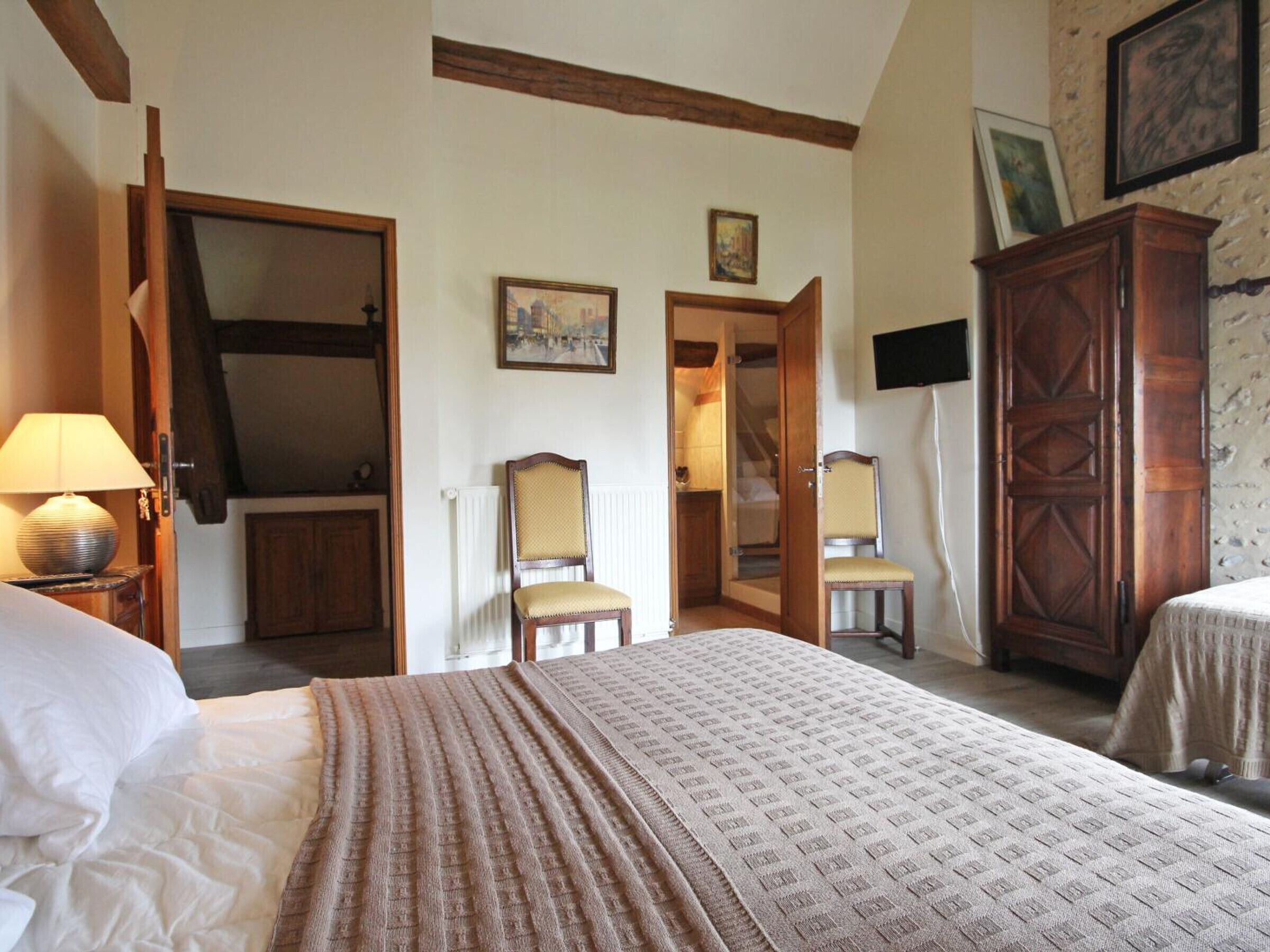A bedroom with a large bed, a wardrobe, a chair, and a desk.