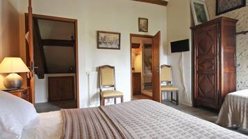 A bedroom with a large bed, a wardrobe, a chair, and a desk.