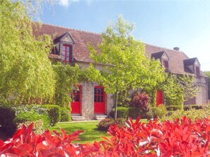 Traditional building with a pitched roof, surrounded by lush greenery and a well-maintained lawn.