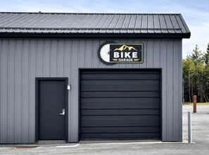 Edificio con puerta de garaje y otra puerta, con la etiqueta 'BIKE GARAGE'.