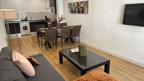 A modern living room with a sofa, coffee table, and dining area. - Charming Renovated Apartment with Cathedral View in Central Málaga (Málaga)