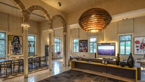 Un interior espacioso con techos altos, arcos de piedra, un televisor grande y una zona de estar moderna.