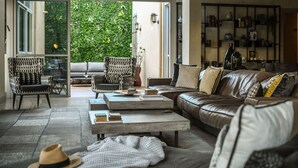 Un salón amplio con un sofá de cuero, dos sillones, una mesa de centro y una estantería.