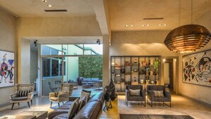 Un salón amplio con un sofá moderno, sillones y una estantería. Una ventana grande ofrece vistas al exterior.