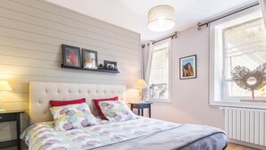 A bedroom with a large bed, a nightstand, a dresser, a window with a view, and a ceiling light. - Spacious house near Cherbourg with enclosed garden and pets allowed (Gonneville-Le Theil)