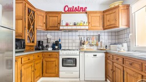 A kitchen with wooden cabinets, a stove, an oven, a dishwasher, and a microwave. - Spacious house near Cherbourg with enclosed garden and pets allowed (Gonneville-Le Theil)