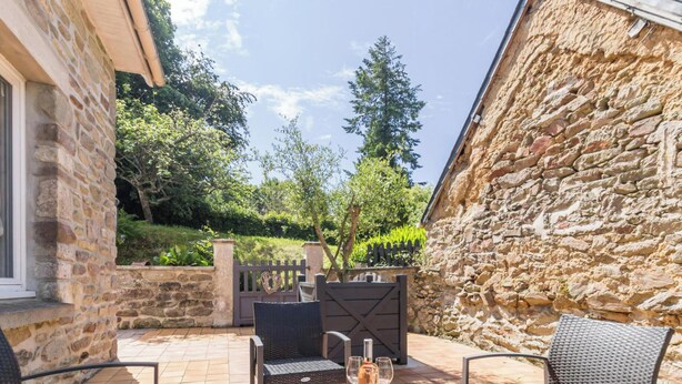 A patio with wicker furniture, a glass table, and a bottle of wine. - Spacious house near Cherbourg with enclosed garden and pets allowed (Gonneville-Le Theil)