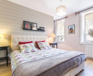 Une chambre à coucher avec un grand lit, une table de chevet, une commode, une fenêtre donnant sur un beau paysage et un luminaire au plafond.