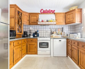 Une cuisine avec des meubles de rangement en bois, une cuisinière, un four, un lave-vaisselle et un four à micro-ondes.