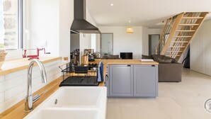 Een moderne keuken met een groot eiland, een ingebouwde oven en een zwarte afzuigkap.