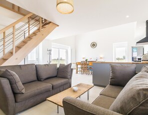 Ein modernes Wohnzimmer mit Sofa, Couchtisch und einer Treppe.
