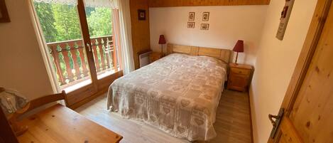 A wooden room with a bed, a table, and a balcony.