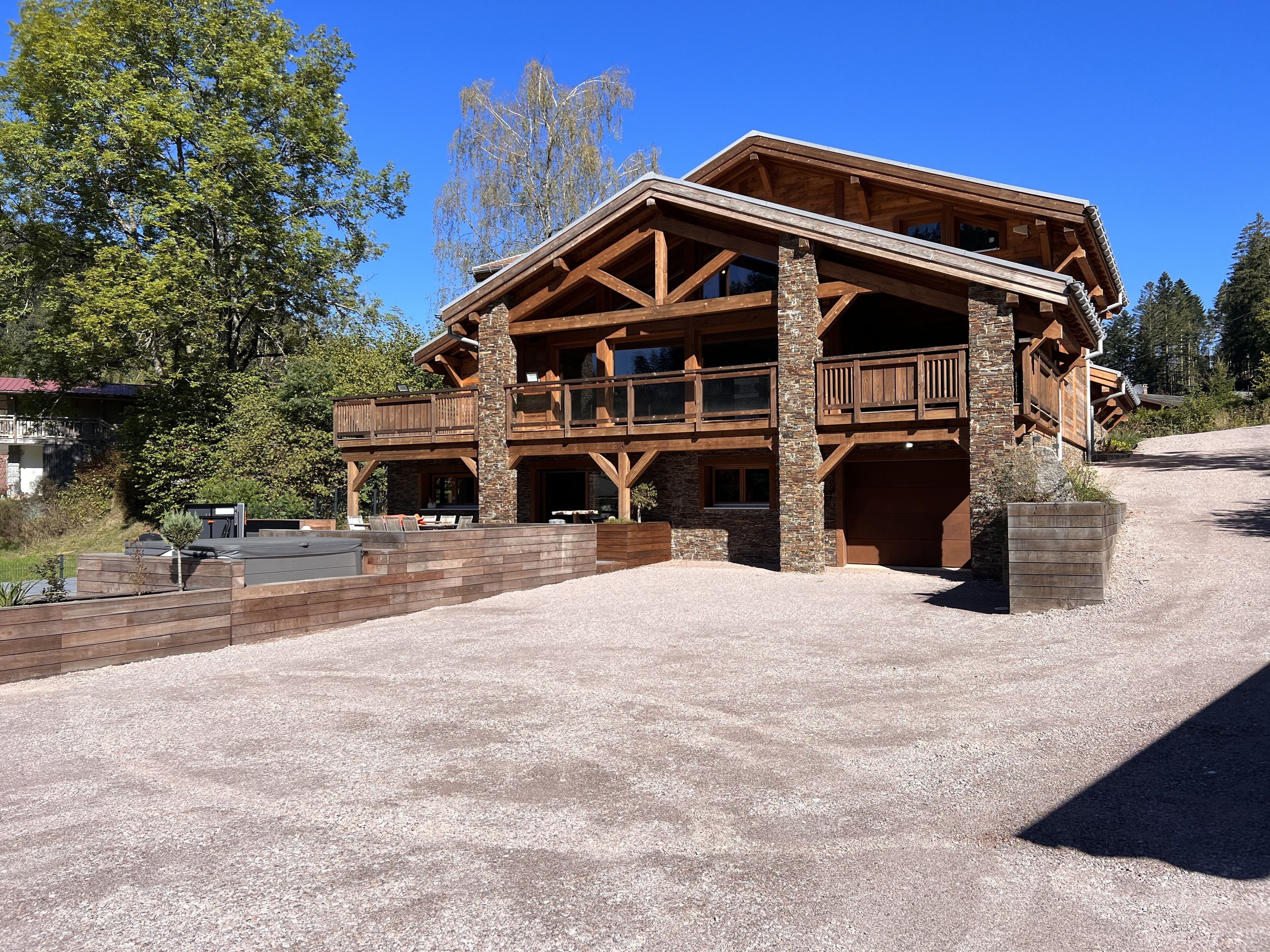 Un amplio lodge de madera con base de piedra, varios balcones y un camino de acceso de grava.