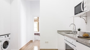 A modern kitchen with a built-in washing machine, a microwave, and a sink. - Charming Apartment Next to Málaga Cathedral with A/C and Free WiFi (Málaga)