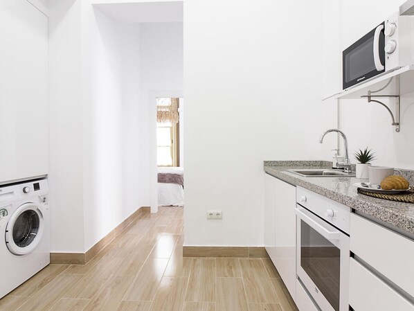 Una cocina moderna con lavadora integrada, microondas y fregadero.