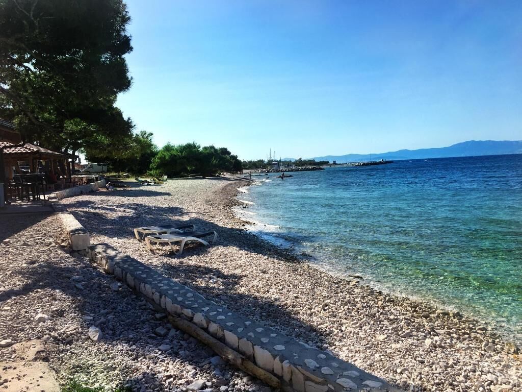 Nær stranden, hvit sand, solsenger og parasoller