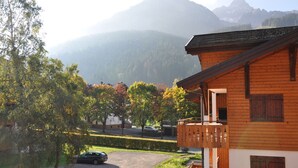 A wooden building with a balcony, surrounded by trees and a mountain in the background. - 3-room apartment with large balcony, parking (La Chapelle-d'Abondance)
