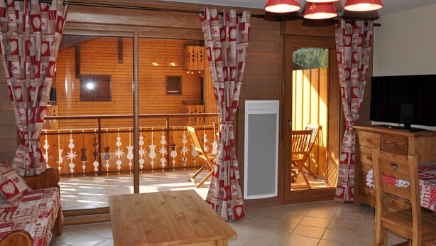 A wooden interior with a sofa, a table, and a TV stand. - 3-room apartment with large balcony, parking (La Chapelle-d'Abondance)