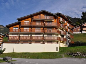 A multi-story hotel with balconies, a flat roof, and a view of the surrounding landscape. - Cozy studio near center, balcony and parking (Châtel)