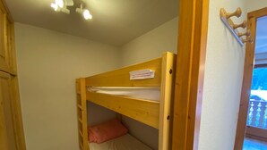 A bunk bed with a wooden frame, a white mattress, and a pink pillow. - Cozy studio near center, balcony and parking (Châtel)