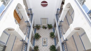 Un edificio de varios niveles con un patio central, balcones y plantas en macetas.