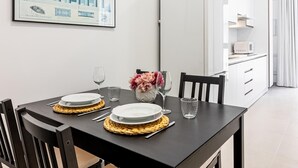 A dining table set with plates, glasses, and a vase of flowers. - Bright Loft in Málaga with A/C, Modern Kitchen, and High-Speed WiFi (Málaga)