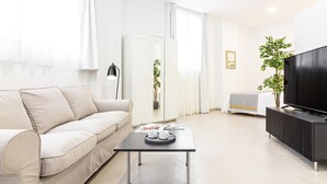 A modern living room with a sofa, a coffee table, a TV, and a cabinet. - Bright Loft in Málaga with A/C, Modern Kitchen, and High-Speed WiFi (Málaga)