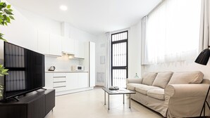 A modern living room with a flat-screen TV on a black stand, a beige sofa, and a small coffee table. - Bright Loft in Málaga with A/C, Modern Kitchen, and High-Speed WiFi (Málaga)