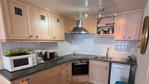 A compact kitchen with wooden cabinets, a microwave, a toaster, a kettle, and a sink. - Apartment with Sunny Terrace in La Chapelle-d'Abondance (La Chapelle-d'Abondance)