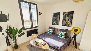 A bedroom with a bed, a bedside table, a window, and a floor lamp.