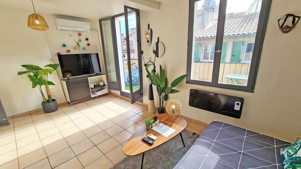 A modern living room with a TV, sofa, and plants.