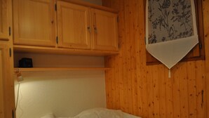 A single bed in a room with wooden walls and a shelf above it. - Charming apartment in Petit-Châtel, pets allowed (Châtel)