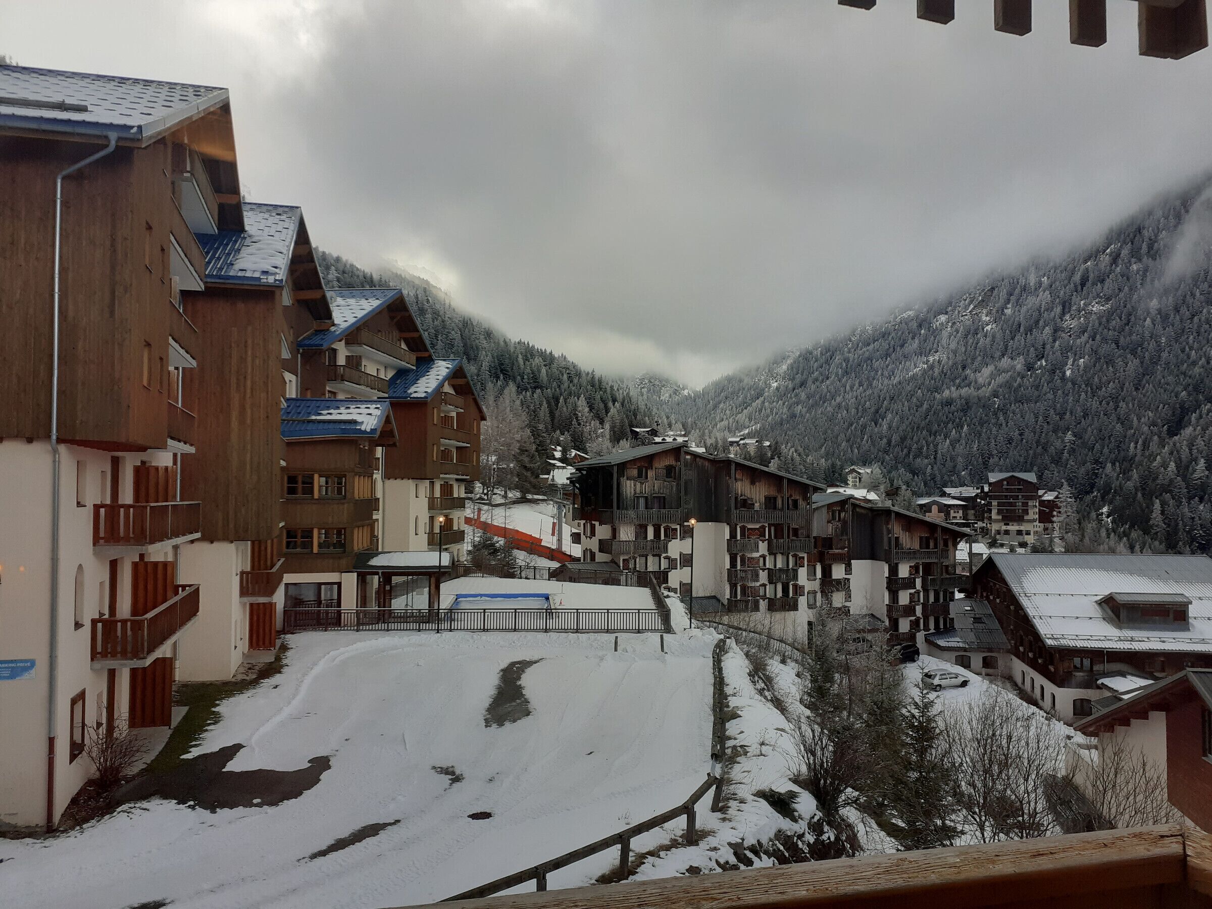 A snow-covered mountain village with wooden buildings and a ski slope.