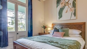 A bedroom with a bed, a nightstand, a window, and a wall-mounted artwork. - 2 mins walking to harbour bridge (Dawes Point)