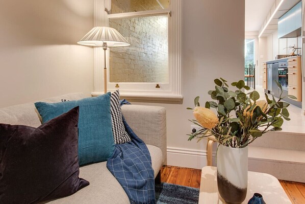 A modern living room with a sofa, cushions, a lamp, and a plant. - 2 mins walking to harbour bridge (Dawes Point)