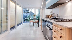 A modern kitchen with a central island, built-in appliances, and a view of a garden. - 2 mins walking to harbour bridge (Dawes Point)