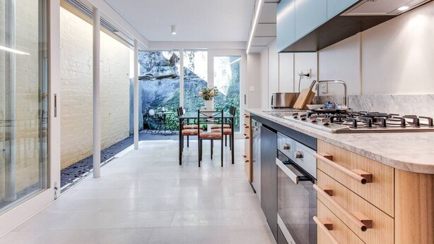 A modern kitchen with a central island, built-in appliances, and a view of a garden. - 2 mins walking to harbour bridge (Dawes Point)