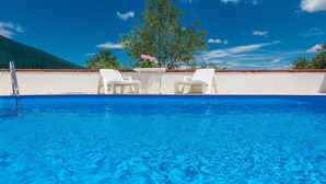 A clear blue pool with white lounge chairs and a table, surrounded by a white wall and a tree. - Stunning home in Bila Vlaka (Bila Vlaka)