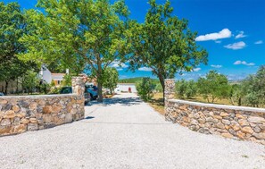 Drive through the tranquil landscape to a serene retreat with a Mediterranean-style building in the distance.