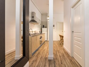 A hallway with wooden flooring, white walls, and a kitchen area with a microwave, sink, and cabinets. - Bright, Newly Renovated 2BR Apt in Historic Center Near Calle Larios (Málaga)