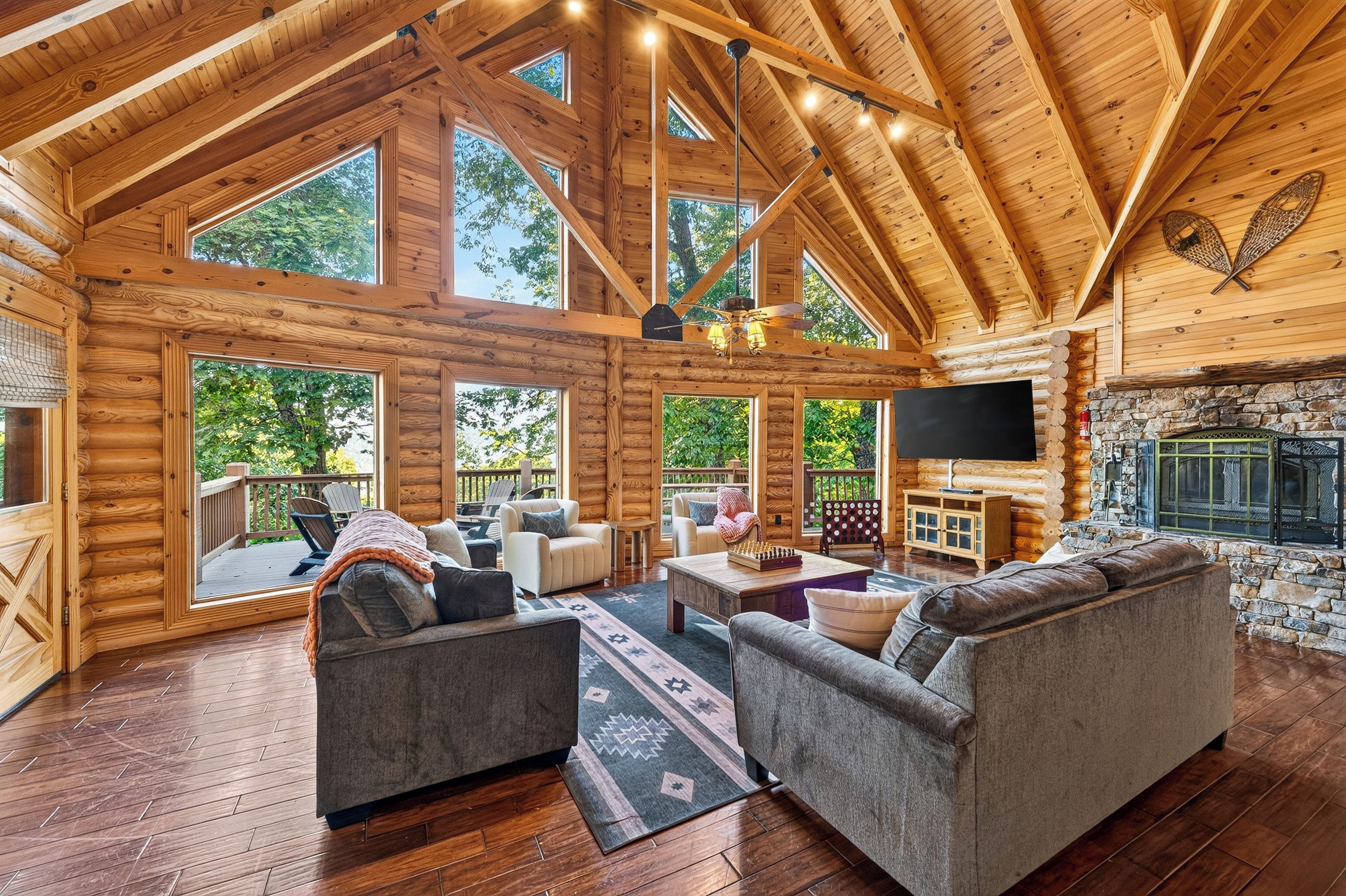 Gather beneath vaulted ceilings around the stone fireplace, with forest views beyond the windows.