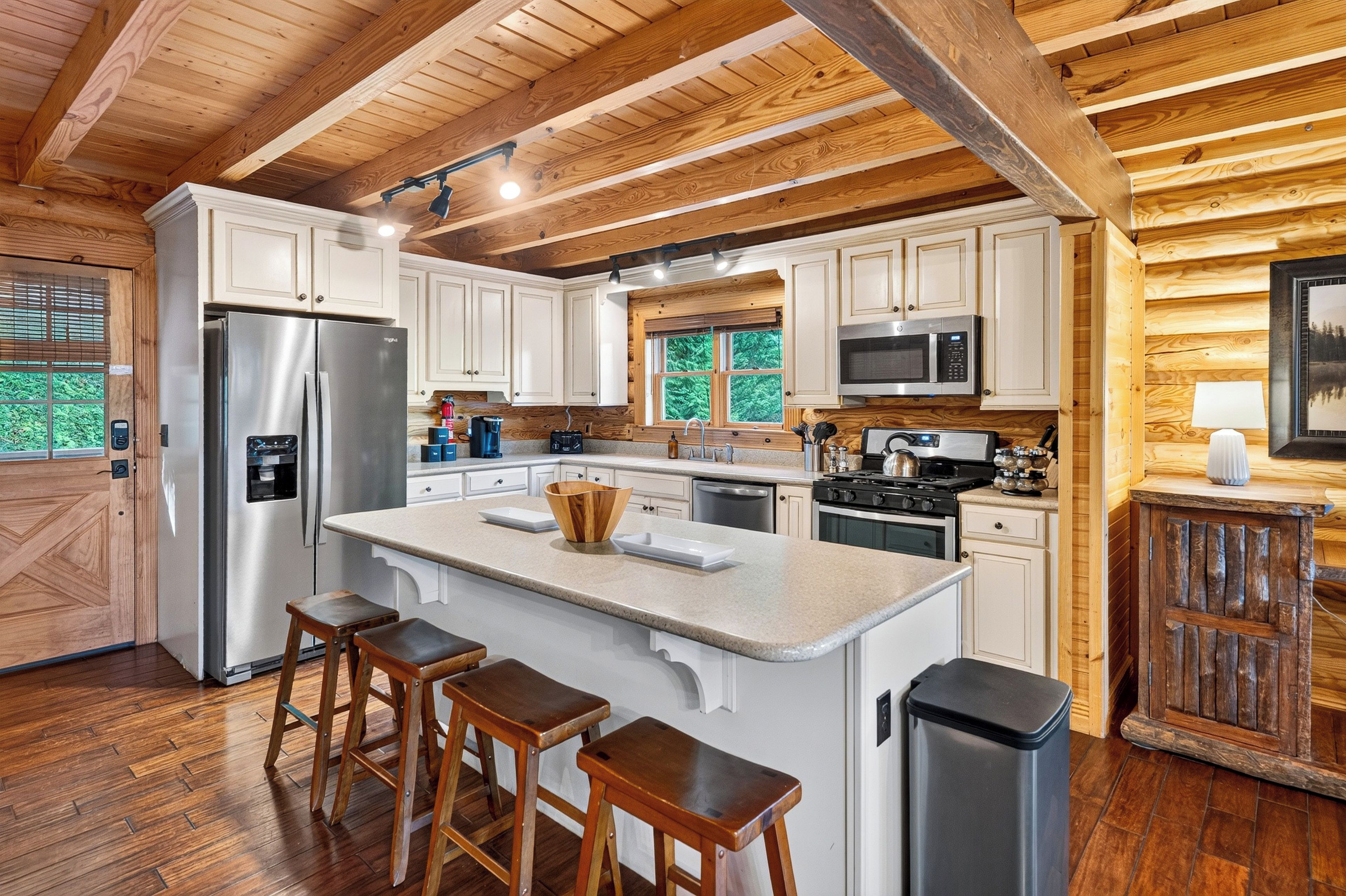 A modern kitchen with wooden beams, stainless steel appliances, and a large island with stools.