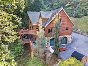 A log cabin with a deck and a stone foundation. - Sleeps 20 | Grand Mountain Lodge • Hot Tub + Sauna + Views | Mountain View Lodge (Asheville)