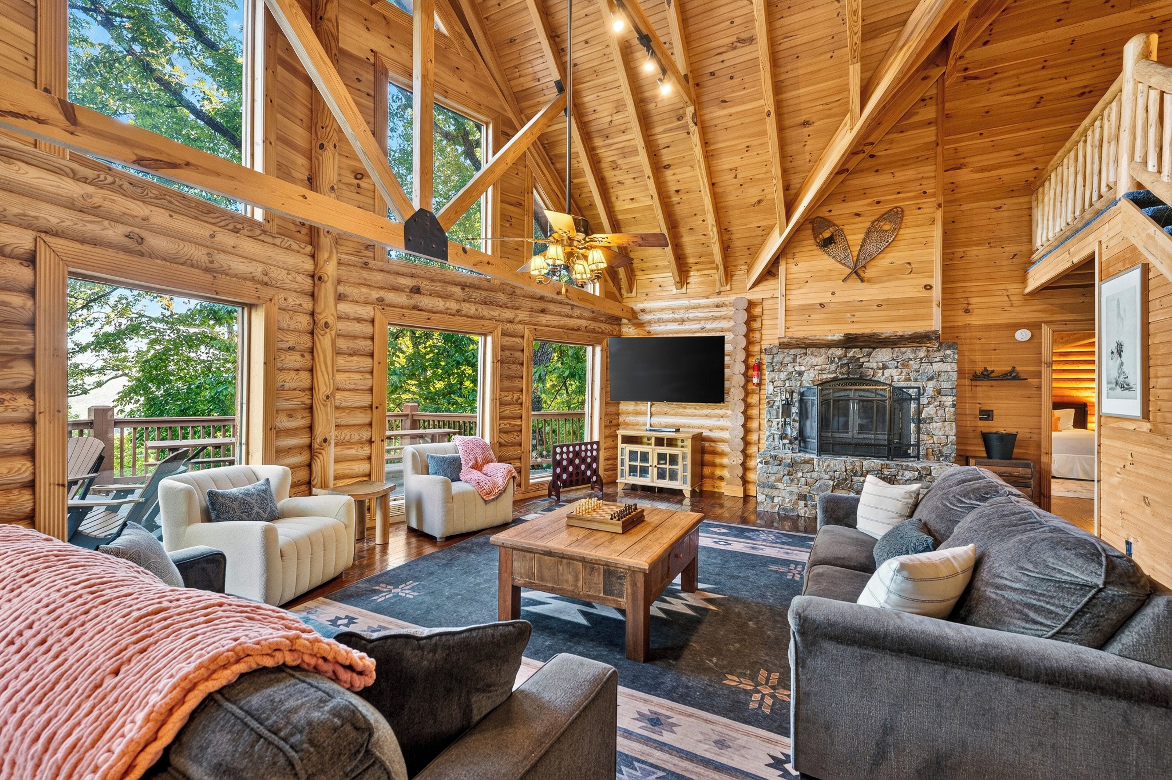 A log cabin interior with a fireplace, wooden furniture, and a television.