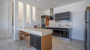 Une cuisine moderne dotée d’un îlot central, d’appareils électroménagers en acier inoxydable et d’un design minimaliste.