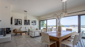 Un salon moderne avec une grande table à manger, des meubles blancs et des œuvres d’art accrochées aux murs.