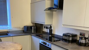 Eine moderne Küche mit weißen Schränken, einem Backofen, einer Mikrowelle, einem Toaster und einem Wasserkocher.