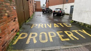 Ein schmaler Gang mit der Aufschrift 'PRIVATE PROPERTY' auf dem Boden.