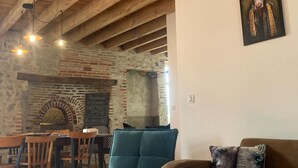 A rustic interior with exposed wooden beams, a brick wall, a brick oven, and a blue sofa. - 19th Century family home with terrace & garden, ideal for 10 people. (Cindré)