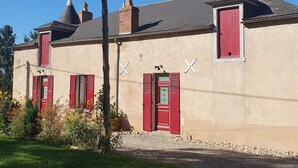 A two-story building with red shutters, a white cross on the facade, and a chimney. - 19th Century family home with terrace & garden, ideal for 10 people. (Cindré)